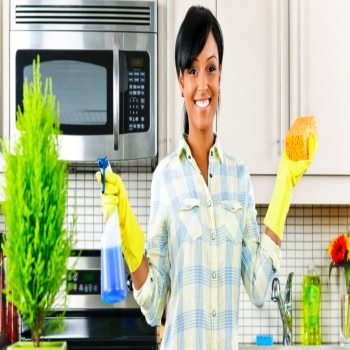 Smiling young black woman with sponge and rubber gloves cleaning kitchen